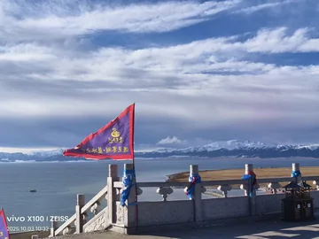 A bright flag above Sayram Lake and snowy mountains